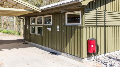 a green house with a red fire hydrant on the side of it at Silkeborg Sø Camping Apartments in Silkeborg
