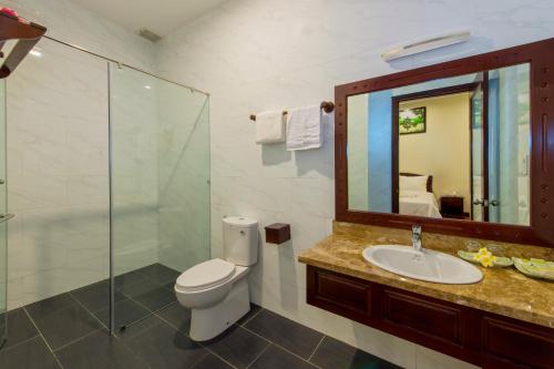 um banheiro com vaso sanitário, pia e espelho em Paradise Indochine Hoi An em Hoi An