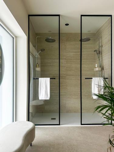 a bathroom with a glass shower with towels at Inspire Residence and private Wellness in Tongeren