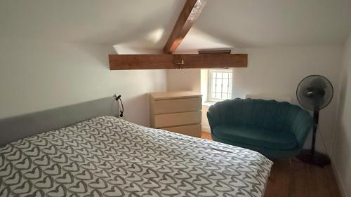 a bedroom with a bed and a blue chair at La Rollinoise in Valsonne