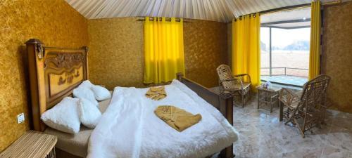 a bedroom with a bed and a table and a window at Rotana camp in Disah