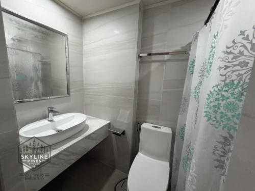 ein Badezimmer mit weißer Toilette und Waschbecken in der Unterkunft Skyline Pines City Hub - Baguio in Baguio City