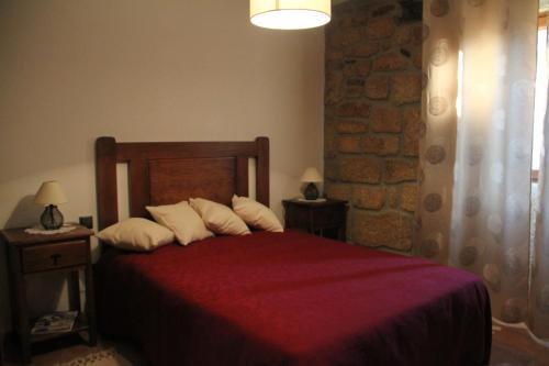 um quarto com uma cama vermelha e almofadas brancas em Alojamento Rural Casa da Eira em Murça