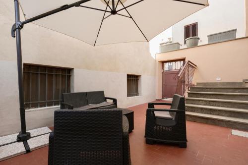 a patio with chairs and an umbrella and stairs at Domus Fabia - Rooms & Apartments in San Gemini