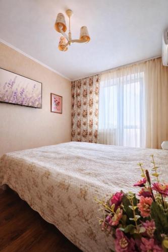 a bedroom with a bed and a window with flowers at Sweet Home on Shevchenko street in Vinnytsya