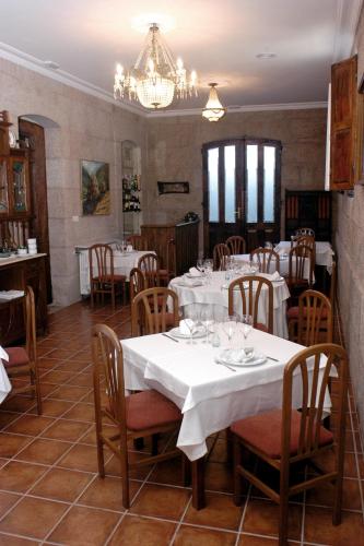 a restaurant with white tables and chairs and a chandelier at Pazo Almuzara in Boborás
