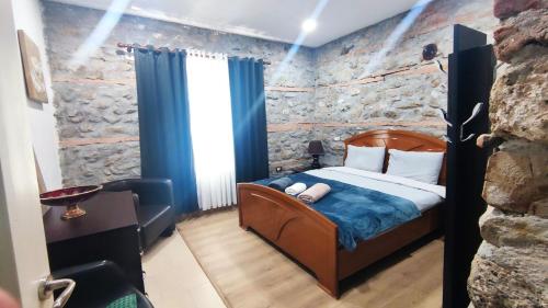 een slaapkamer met een bed en een stenen muur bij Julia's Village Villa in Korçë