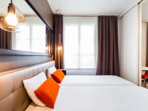 a hotel room with two beds with orange pillows at Aparthotel Adagio Marseille Timone in Marseille