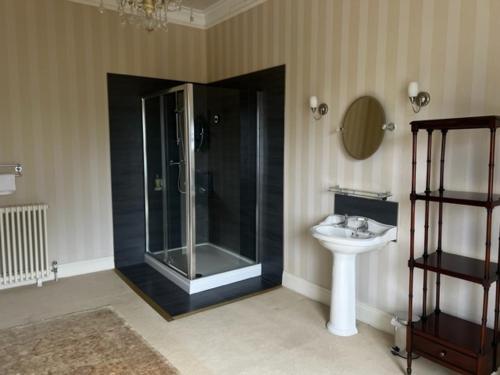 een badkamer met een glazen douche en een wastafel bij Netley Hall in Shrewsbury