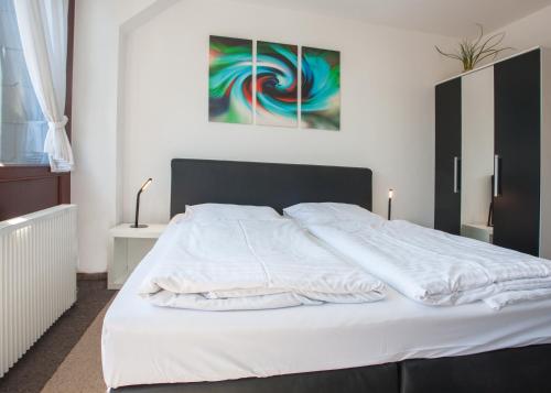 a bedroom with a white bed with a painting on the wall at Welcome in - Studio met balkon, dichtbij skipiste in Winterberg in Winterberg