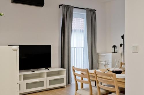 ein Wohnzimmer mit einem Esstisch und einem TV in der Unterkunft Apartamenty IN Leśna in Hel