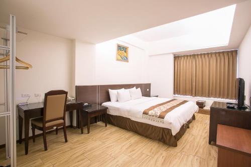 a hotel room with a bed and a desk and a television at Huang Shin Business Hotel-Chung Kang in Taichung