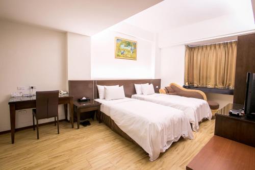 a hotel room with two beds and a desk at Huang Shin Business Hotel-Chung Kang in Taichung