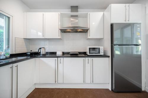 a kitchen with white cabinets and a black refrigerator at Sorrento Pool Villa Bang Lamung Pattaya in Ban Rong Po