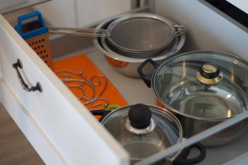 a kitchen counter with pots and pans in a drawer at Ramios bitės in Palanga