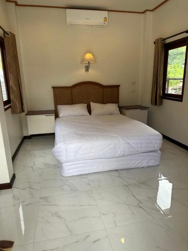 een slaapkamer met een groot bed met witte lakens bij บ้านพิมพ์วนาเขาใหญ่ ห้องมินิ in Ban Tha Maprang