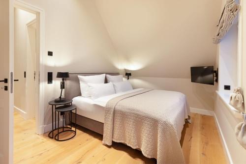 een slaapkamer met een bed met witte lakens en een tafel bij Dünenhafer in List