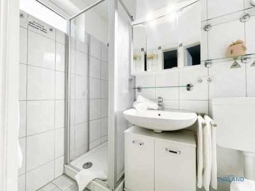 een witte badkamer met een wastafel en een douche bij Haus Nautic Wohnung 615 in Döse