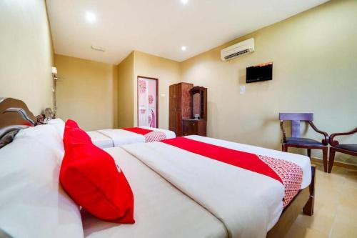 a bedroom with three beds with red and white sheets at OYO 44058 MOTEL SRE BAYAM in Kampong Ayer Hitam