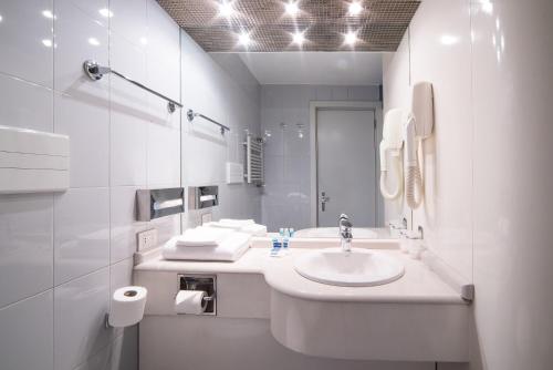 a white bathroom with a sink and a mirror at Idea Hotel Piacenza in Piacenza