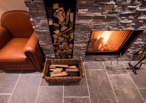 a fireplace with a couch and a basket of wood at Riffelhaus 1853 in Zermatt