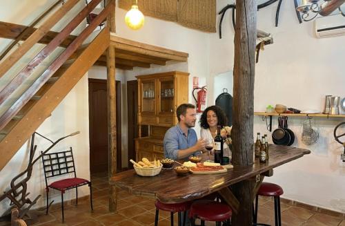 un homme et une femme assis à une table avec un verre de vin dans l'établissement Casa Rural Privada Arenosos, à Pruna