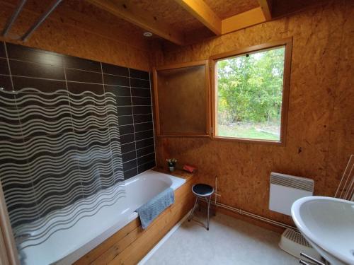 un bagno con vasca, lavandino e finestra di Gîte Chalet Morvan Bourgogne a Corancy