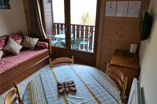 a room with a table and a couch and a balcony at Studio au pied des pistes - Vue montagne in Saint-Jean-d'Aulps