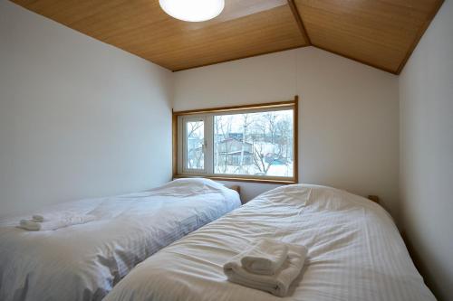 two beds in a small room with a window at HETA Niseko in Niseko