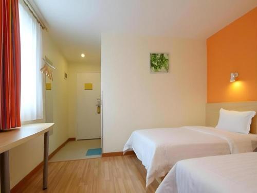 a hotel room with two beds and a window at 7 Days Inn Wuhan Hanyang Wanda Plaza in Wuhan
