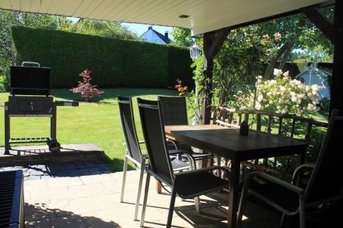 a patio with a table and chairs and a grill at Wohnen im bergischen Fachwerk in Overath