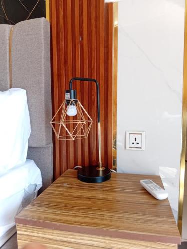 een lamp op een houten tafel naast een bed bij Mars Camp, Lunar Space in Wadi Rum