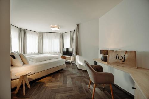 ein Schlafzimmer mit einem Bett, einem Schreibtisch und einem Stuhl in der Unterkunft Hotel loj - our kind of place in Flachau