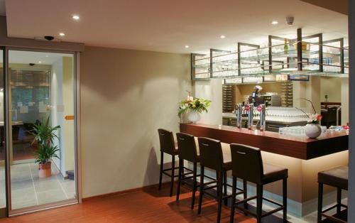 a dining room with a bar with black chairs at Hotel de modern in Diest