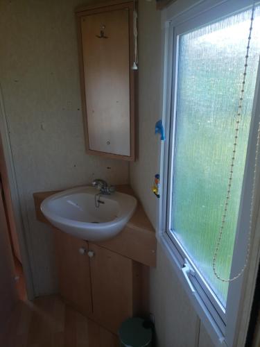 ein kleines Badezimmer mit Waschbecken und Fenster in der Unterkunft l Aire Tranquille in Hamtelle