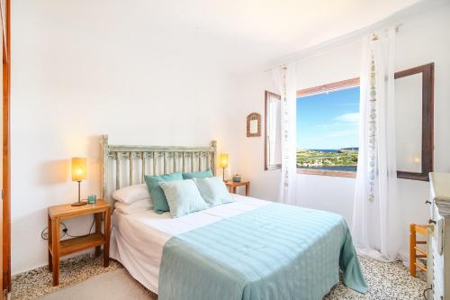 une chambre blanche avec un lit et une fenêtre dans l'établissement Chalet Addaya, à Port d'Addaia