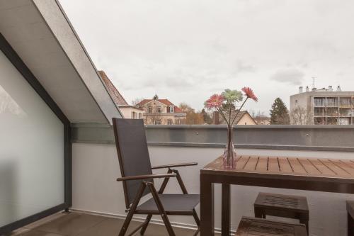 a balcony with a table and a chair and a vase with flowers at Résidence Pierre & Vacances La Petite Venise in Colmar
