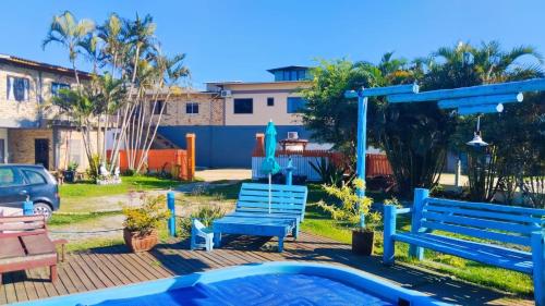 a yard with two blue benches and a pool at Pousada Horizontes do Rosa in Praia do Rosa
