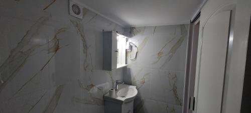 ein Badezimmer mit Waschbecken und weißer Marmorwand in der Unterkunft Helios nest in Artemida