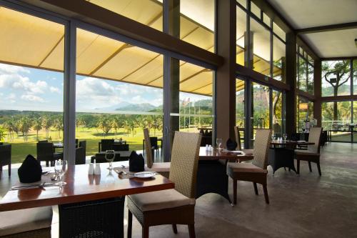 ein Restaurant mit Tischen und Stühlen und großen Fenstern in der Unterkunft Victoria Golf Resort in Digana