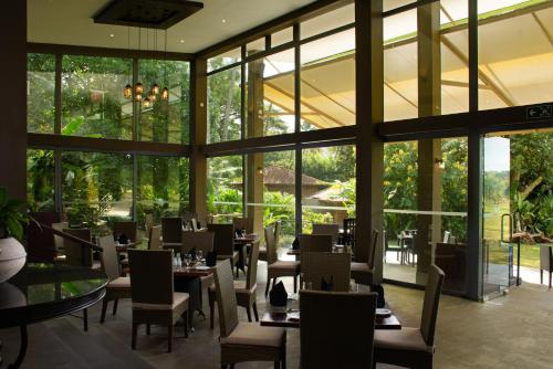 ein Restaurant mit Tischen und Stühlen und großen Fenstern in der Unterkunft Victoria Golf Resort in Digana