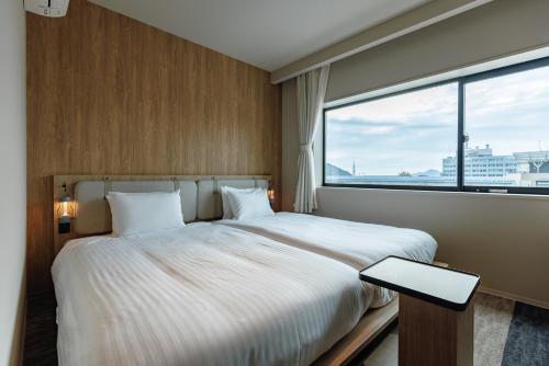 a bedroom with a large bed and a large window at Setouchi Cycle Stays Hiroshima Ujina in Hiroshima