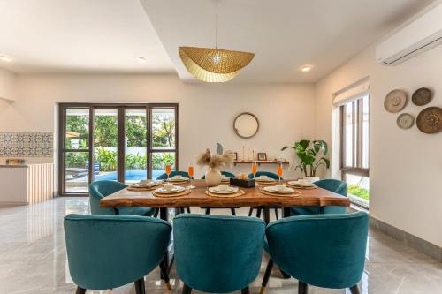 a dining room with a wooden table and blue chairs at ELIVAAS Signature Casa Del Mundo With Pvt Pool, Bar, Lift & Scenic Hill Vistas in Vagator