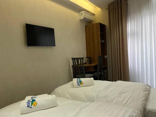 ein Hotelzimmer mit 2 Betten und einem TV an der Wand in der Unterkunft Chotqol sanatorium in G‘azalkent