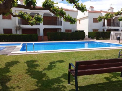 a swimming pool with a bench in front of a building at Elisenda in Vinarós