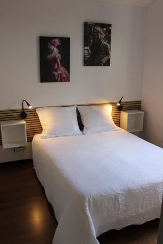 ein Schlafzimmer mit einem weißen Bett mit zwei Bildern an der Wand in der Unterkunft La petite maison in Cuxac-Cabardès