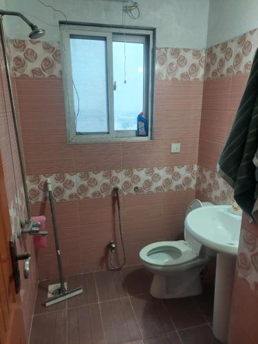 a bathroom with a toilet and a sink and a window at SerenityINn in Islamabad