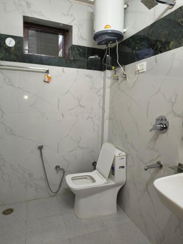 a white bathroom with a toilet and a sink at Parashar lake Fogg hill Resort in Prashar lake
