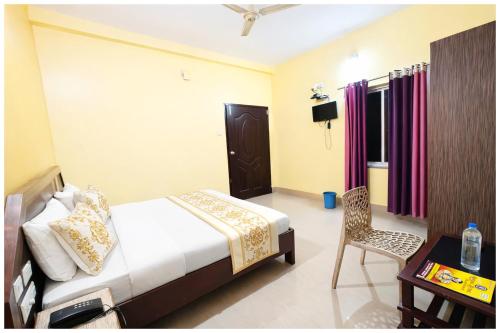 ein Schlafzimmer mit einem Bett, einem Tisch und einem Stuhl in der Unterkunft Chakra Tirtha Road Hotel Premium D2 Stay Near Sea Beach - WiFi # Parking And Restaurant Facilities- Budget Hotel In Puri in Puri
