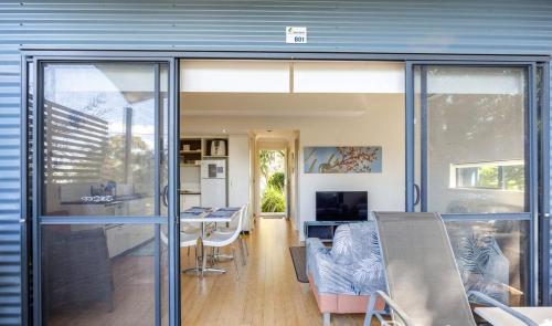 a dining room and kitchen with a sliding glass door at Relaxing Beach shack at the Footprints complex in Preston Beach